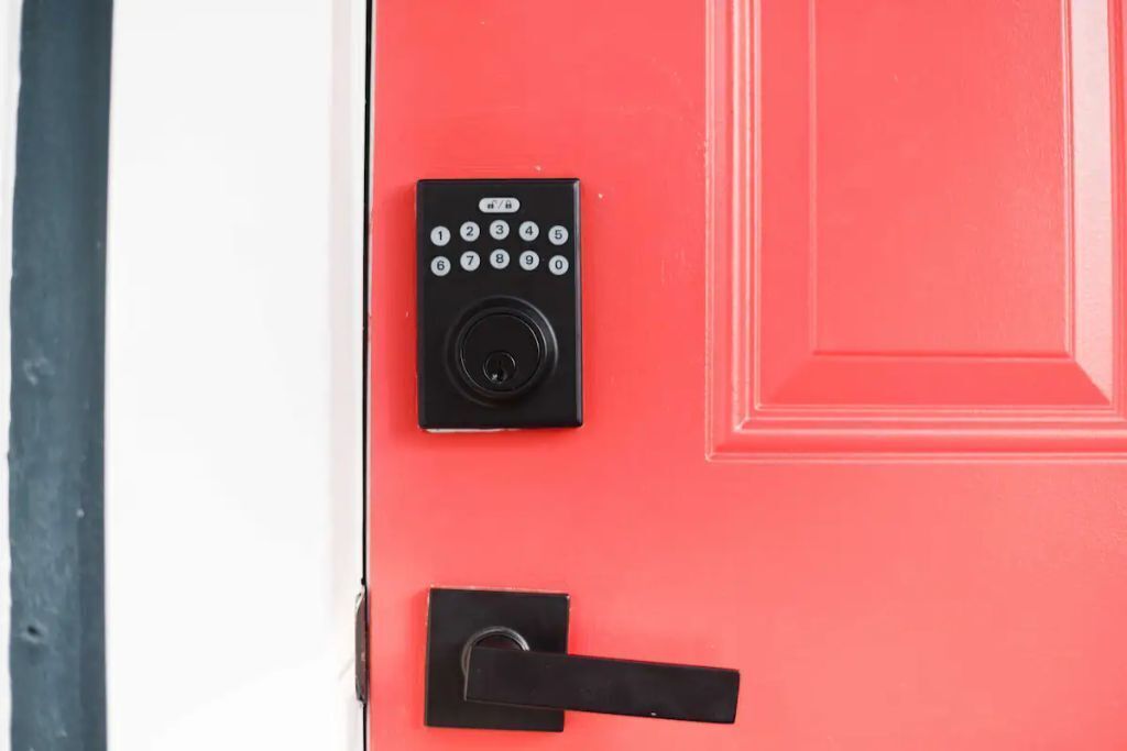 Una puerta roja con un picaporte negro y una cerradura con teclado.