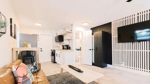 Un soggiorno moderno con un divano in pelle, un tavolino da caffè e una zona cucina sullo sfondo.