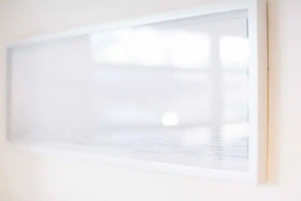 A room with a large window, a white wall, and a door.