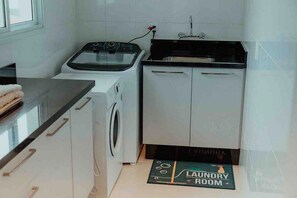 A compact kitchen with a washing machine, a sink, and a countertop.