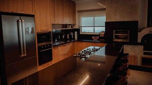 A modern kitchen with wooden cabinets, stainless steel appliances, and a large window providing natural light.