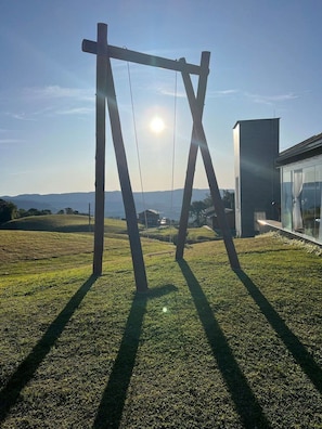 A modern building with a glass facade and a grassy lawn. - Casa Paraíso do Sol - Rancho Queimado (Rancho Queimado)