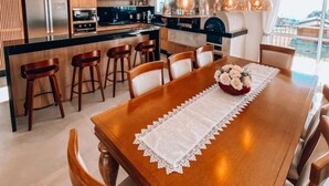 Een moderne keuken met houten kastjes, een roestvrijstalen koelkast en een eethoek met een houten tafel en stoelen.