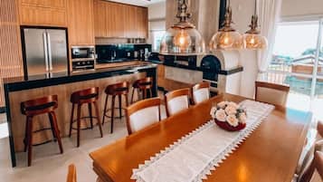 Une cuisine moderne avec des meubles en bois, un réfrigérateur en acier inoxydable et un coin repas comprenant une table et des chaises en bois.