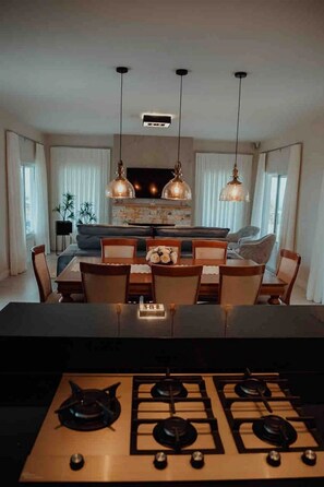 A modern kitchen with a gas stove, dining table, and chairs.