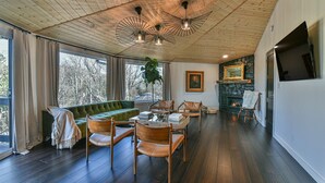 A spacious living room with a wooden ceiling, a green sofa, leather chairs, a glass coffee table, and a fireplace. - La Maison Mirch - Luxe Design Retreat (Asheville)