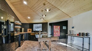 A modern kitchen with a herringbone floor, wooden ceiling, and black cabinetry. - La Maison Mirch - Luxe Design Retreat (Asheville)
