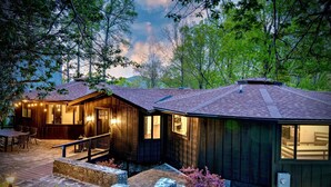 A wooden cabin with a stone patio, outdoor seating, and a staircase leading to a deck. - La Maison Mirch - Luxe Design Retreat (Asheville)