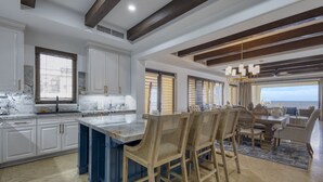 A spacious kitchen with a large island, white cabinetry, and a view to the outside.