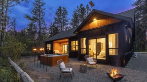 Une cabane moderne dotée d’une grande terrasse, d’un espace salon extérieur et d’un foyer.