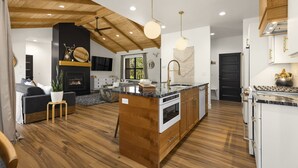 Une cuisine moderne dotée d’un îlot central, de planchers en bois et d’une cheminée.