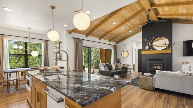 Une cuisine moderne dotée d’un grand îlot central, d’un plafond en bois et d’une cheminée.