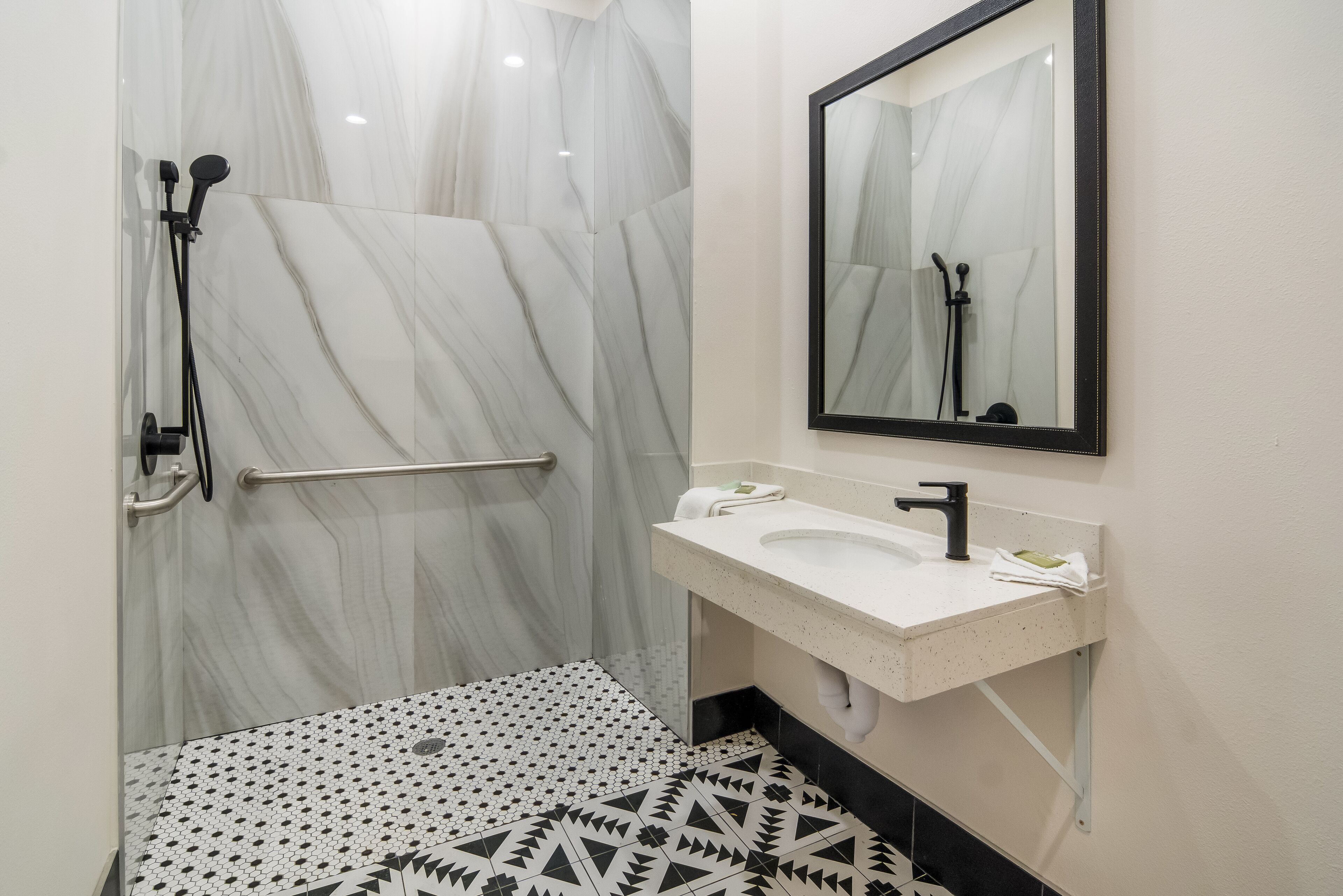 A bathroom with a shower, a sink, and a mirror.