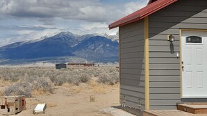 Une maison avec un toit rouge, une porte blanche et une vue sur les montagnes en arrière-plan.