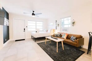 A modern living room with a bed, a brown sofa, a coffee table, and a ceiling fan.