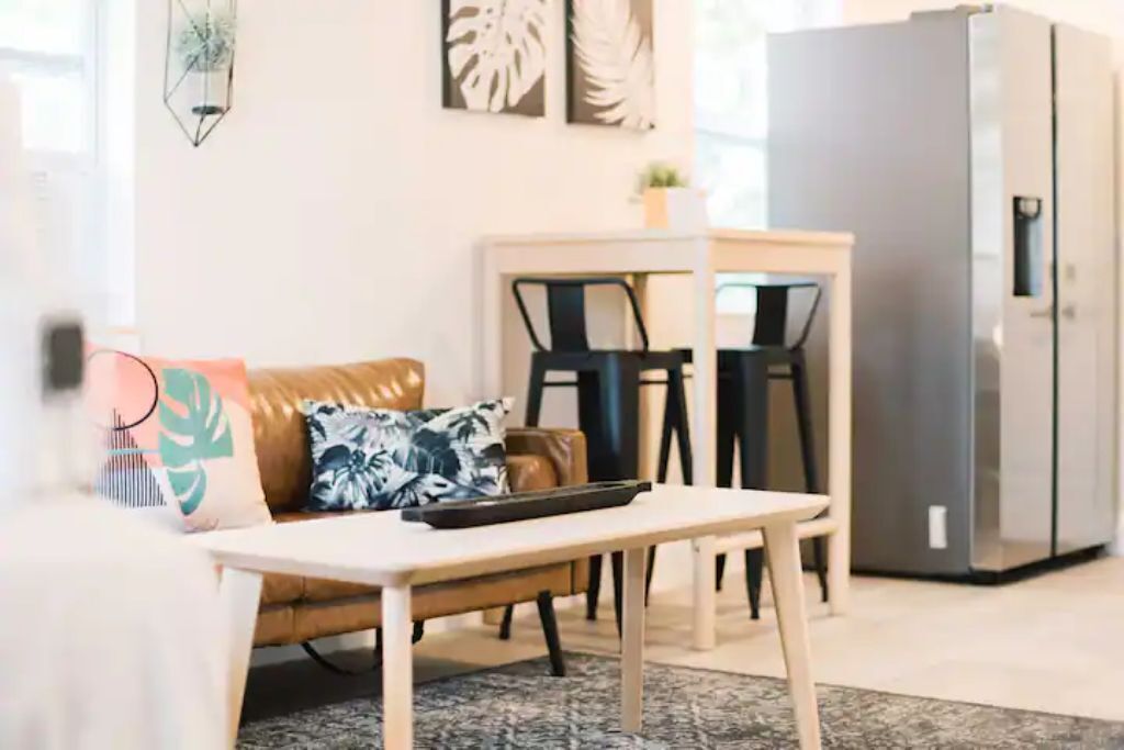 A modern living room with a sofa, a dining table, and a refrigerator.