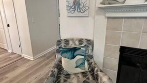 Una sala de estar moderna con un sillón estampado, una chimenea y dos obras de arte colgadas en la pared.