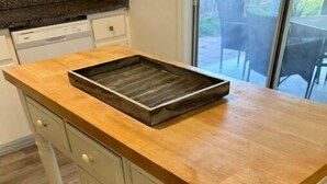 Una cocina con encimera de madera, armarios blancos y una puerta corrediza de vidrio que da a un espacio exterior.