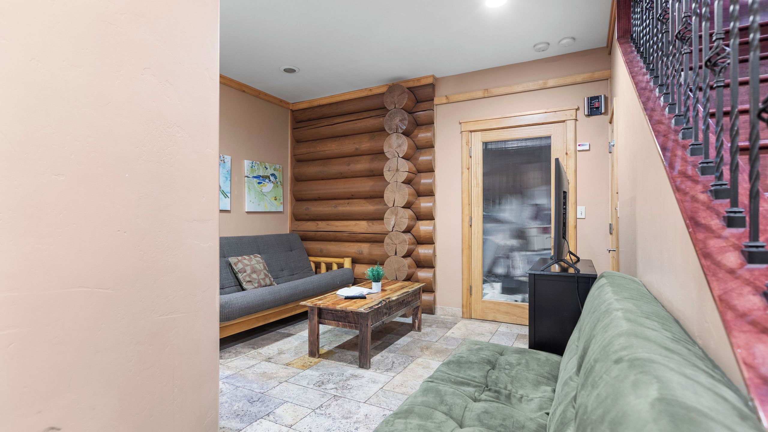 A log cabin interior with a sofa, a coffee table, and a television.