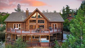 A log cabin with a balcony, a hot tub, and a fireplace.