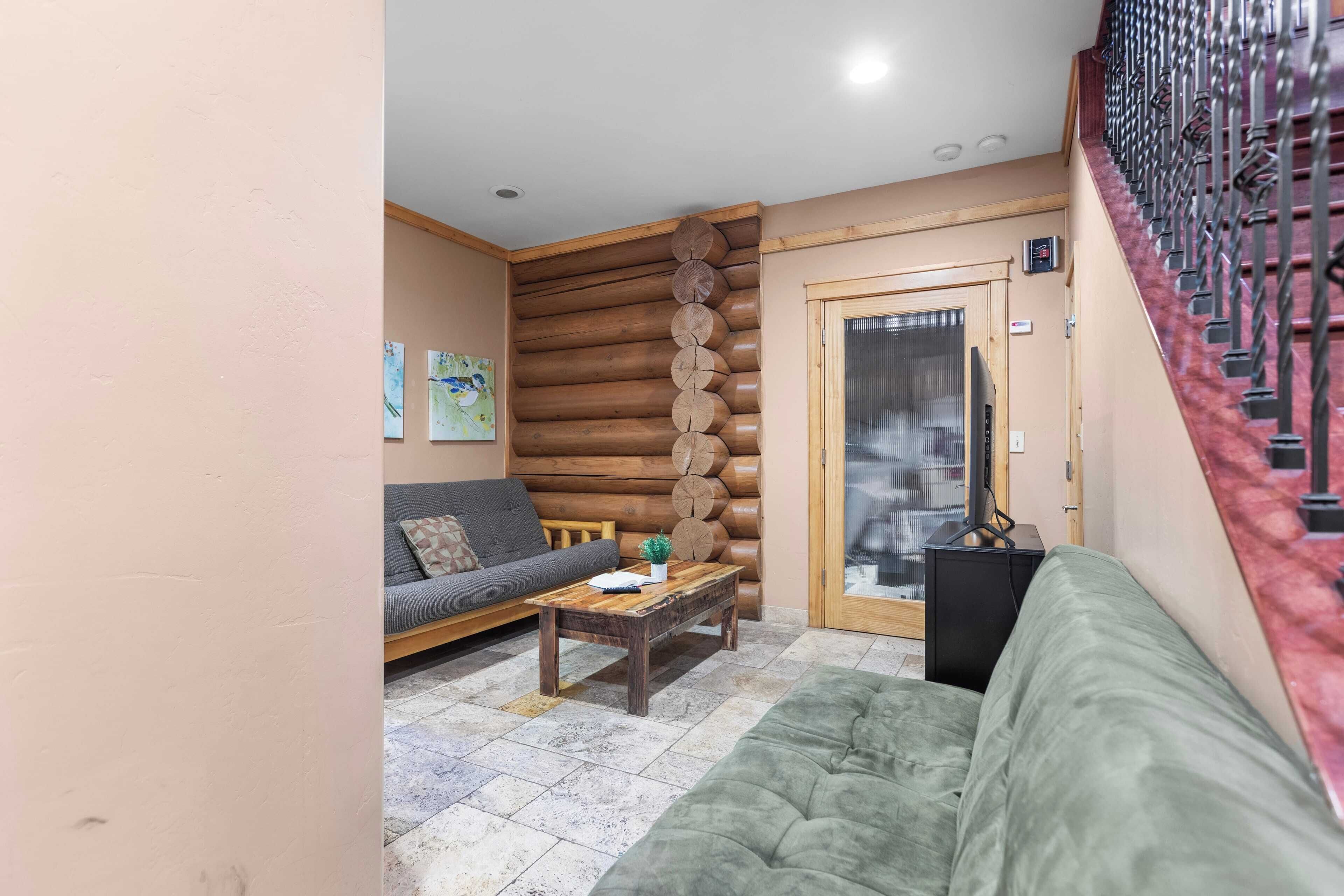 A living room with a sofa, a coffee table, and a log wall.