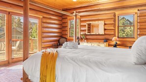 A log cabin bedroom with a large bed, wooden walls, and a ceiling light.