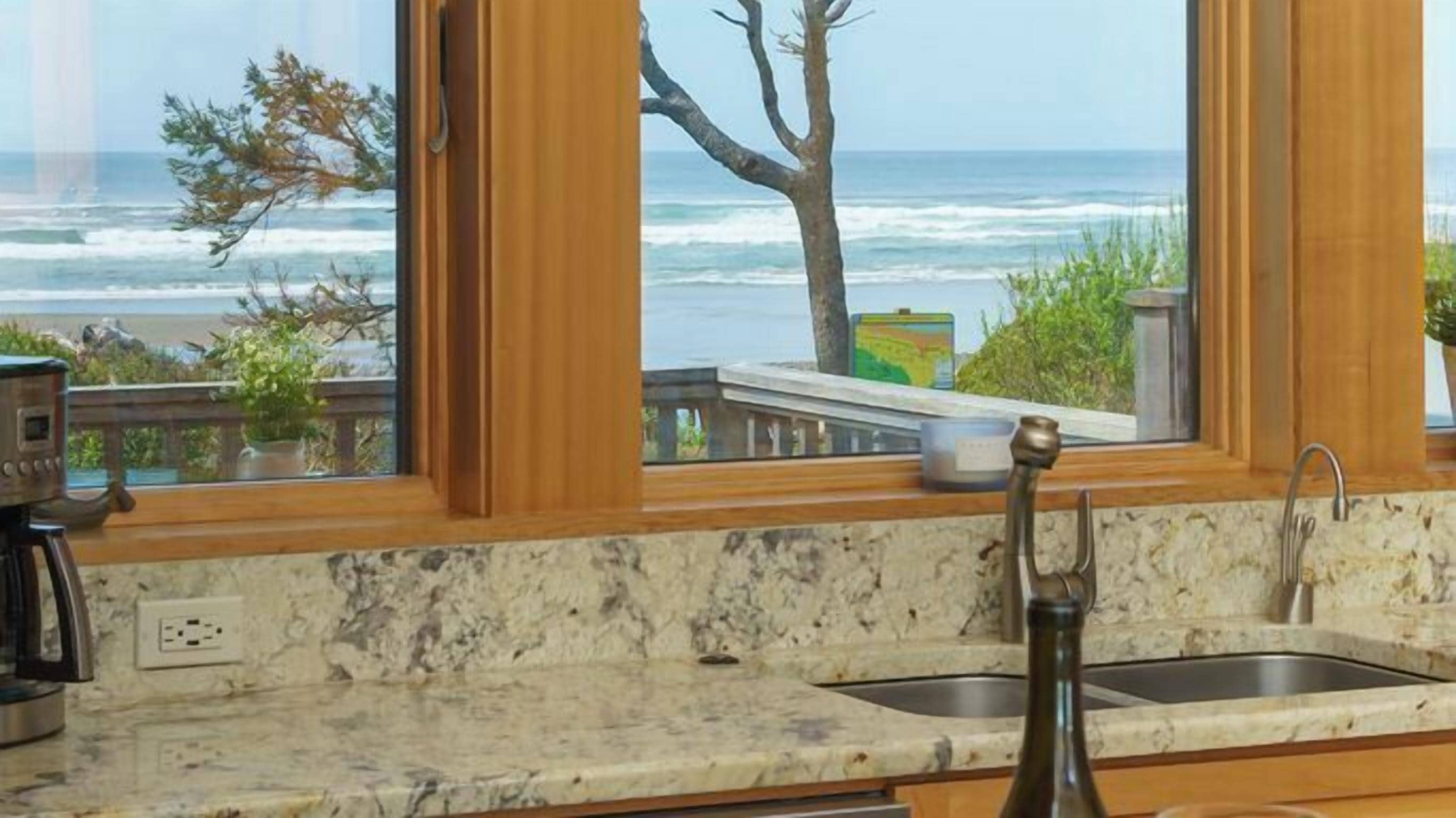 A kitchen with a view of the ocean, a marble countertop, and a sink.
