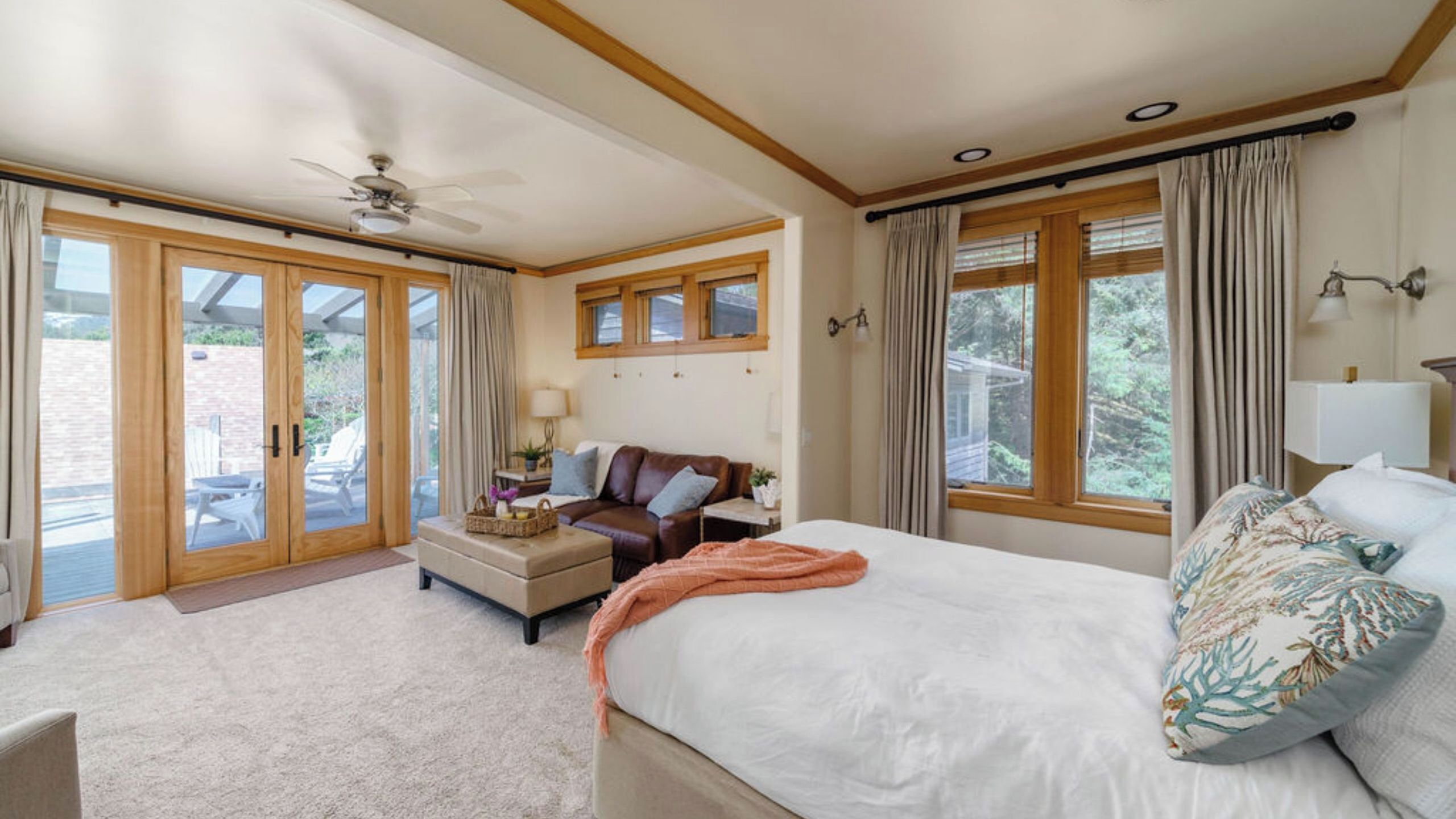 A bedroom with a bed, a sofa, a coffee table, and a ceiling fan.