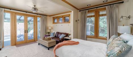 A bedroom with a bed, a sofa, a coffee table, and a ceiling fan.