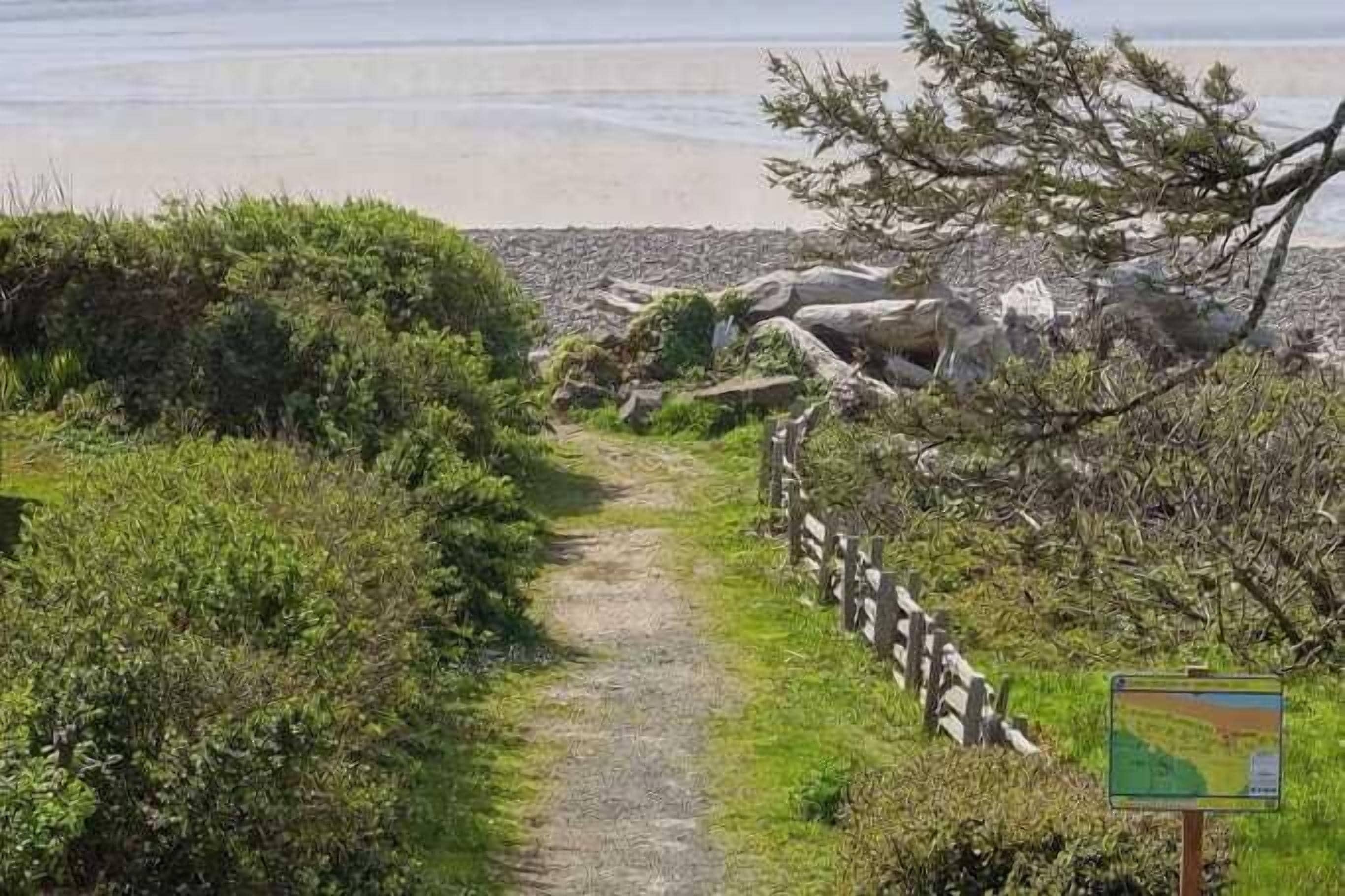A coastal path with a wooden fence, a map sign, and a view of the sea.