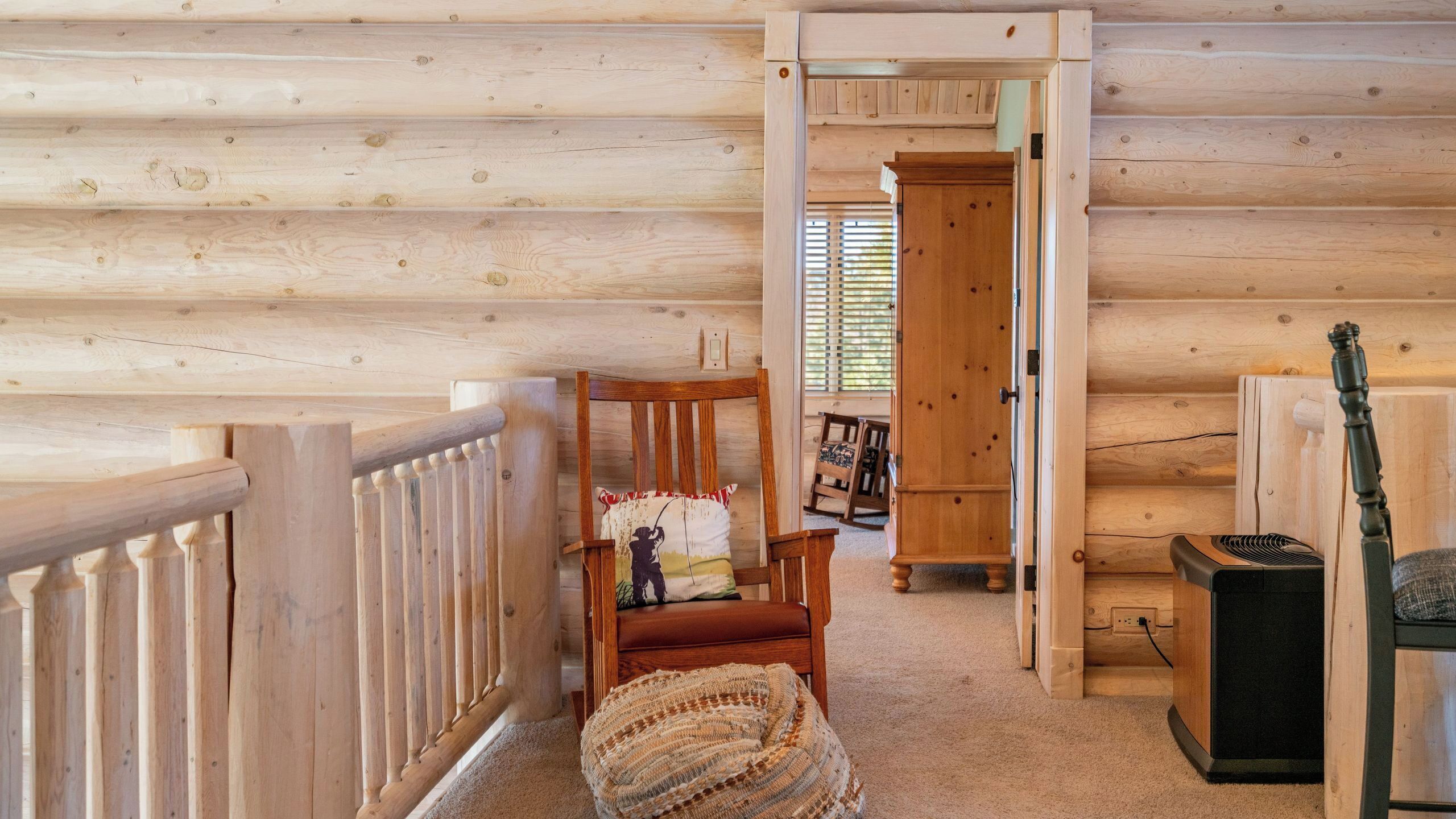 Interior de una cabaña de madera con una silla, una manta tejida y una guitarra.