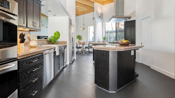 Une cuisine moderne avec des meubles en bois foncé, des appareils électroménagers en acier inoxydable et un îlot central.