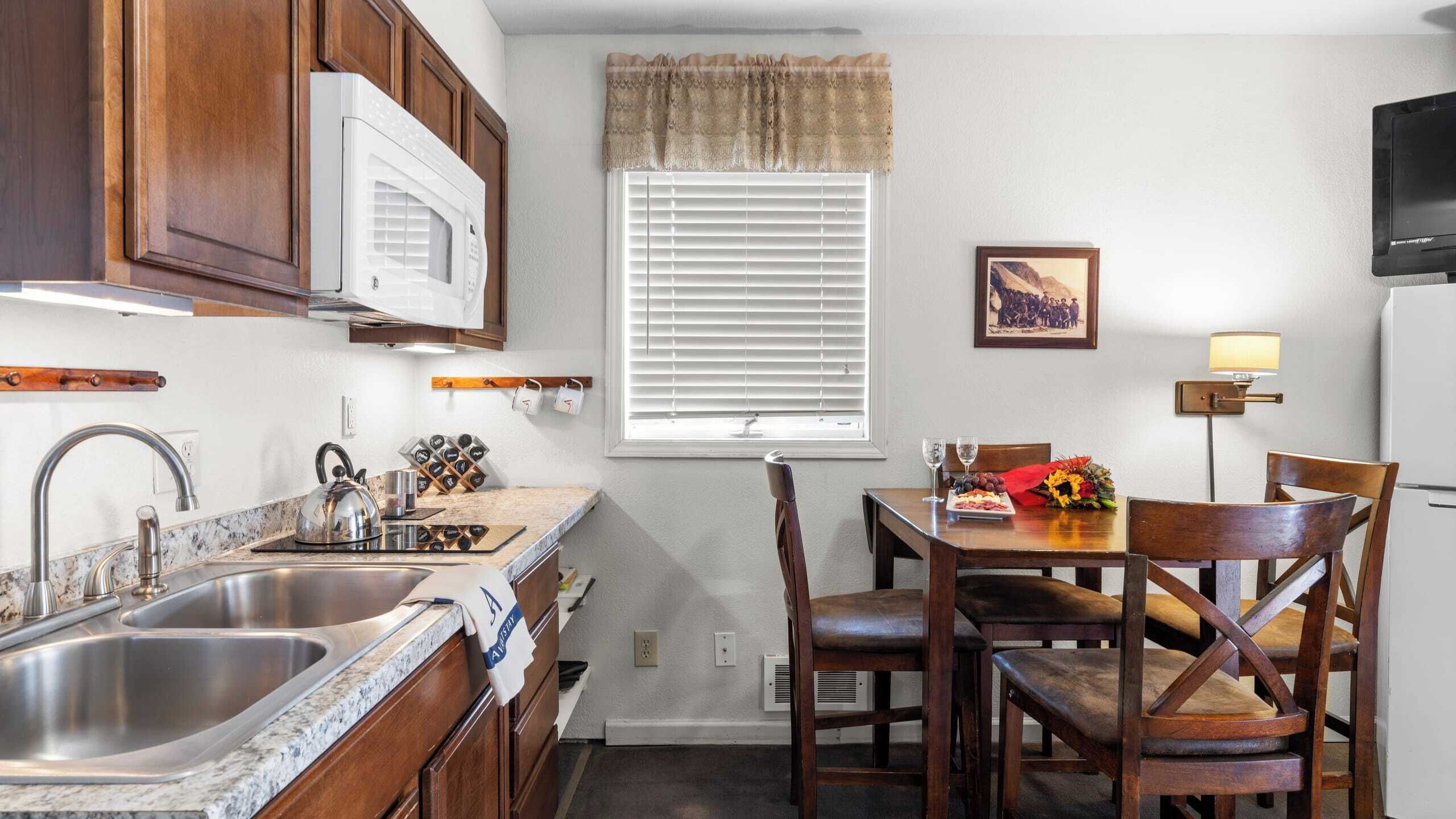 A compact kitchen with a double sink, a microwave, and a dining area with a table and chairs.
