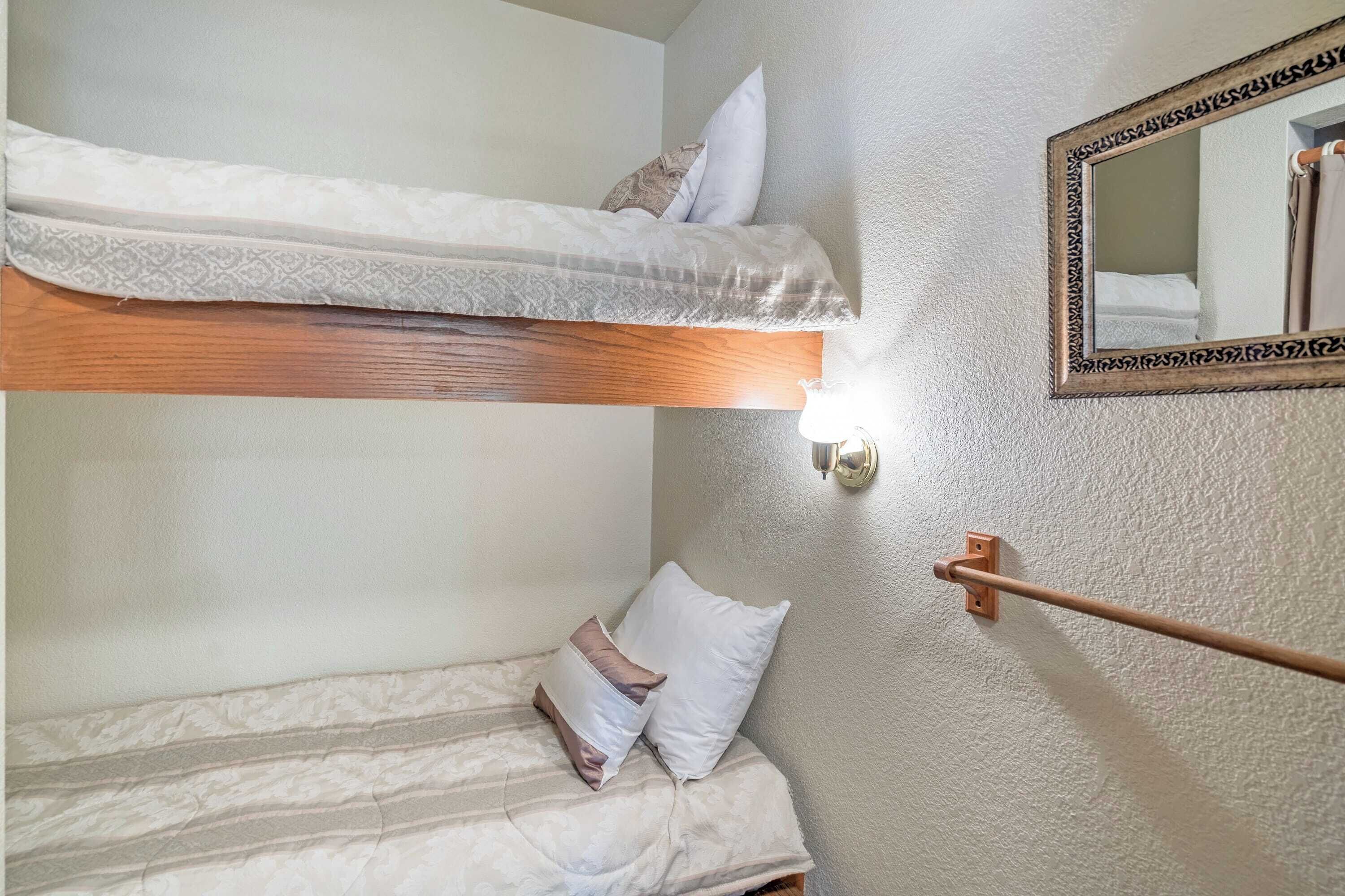 A bunk bed with a wooden headboard, a bedside table with a mirror, and a towel rack.