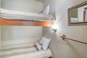 Uma cama de solteiro com cabeceira de madeira, mesa de cabeceira com espelho e porta-toalhas.