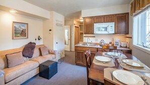 Un espacio habitable compacto con kitchenette, comedor y sofá con manta.