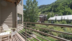 Un balcón con vistas a un paisaje boscoso y un edificio al fondo.