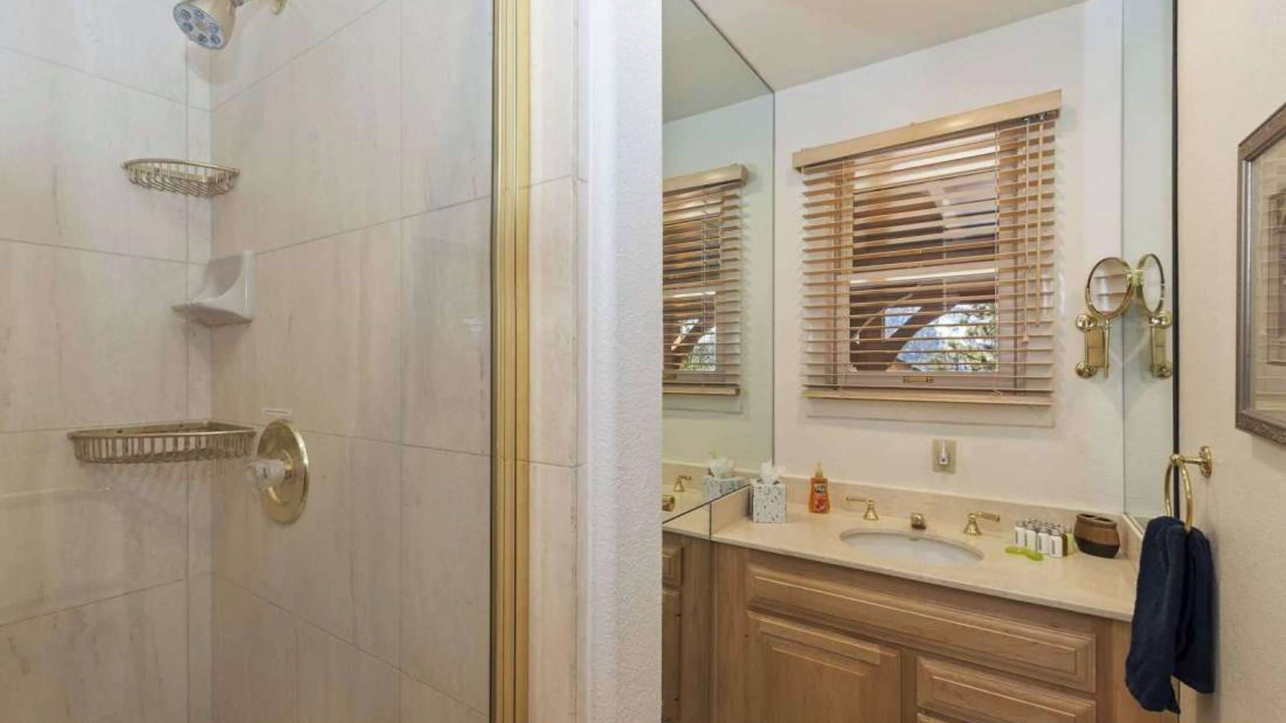 A bathroom with a shower, a sink, and wooden cabinets.