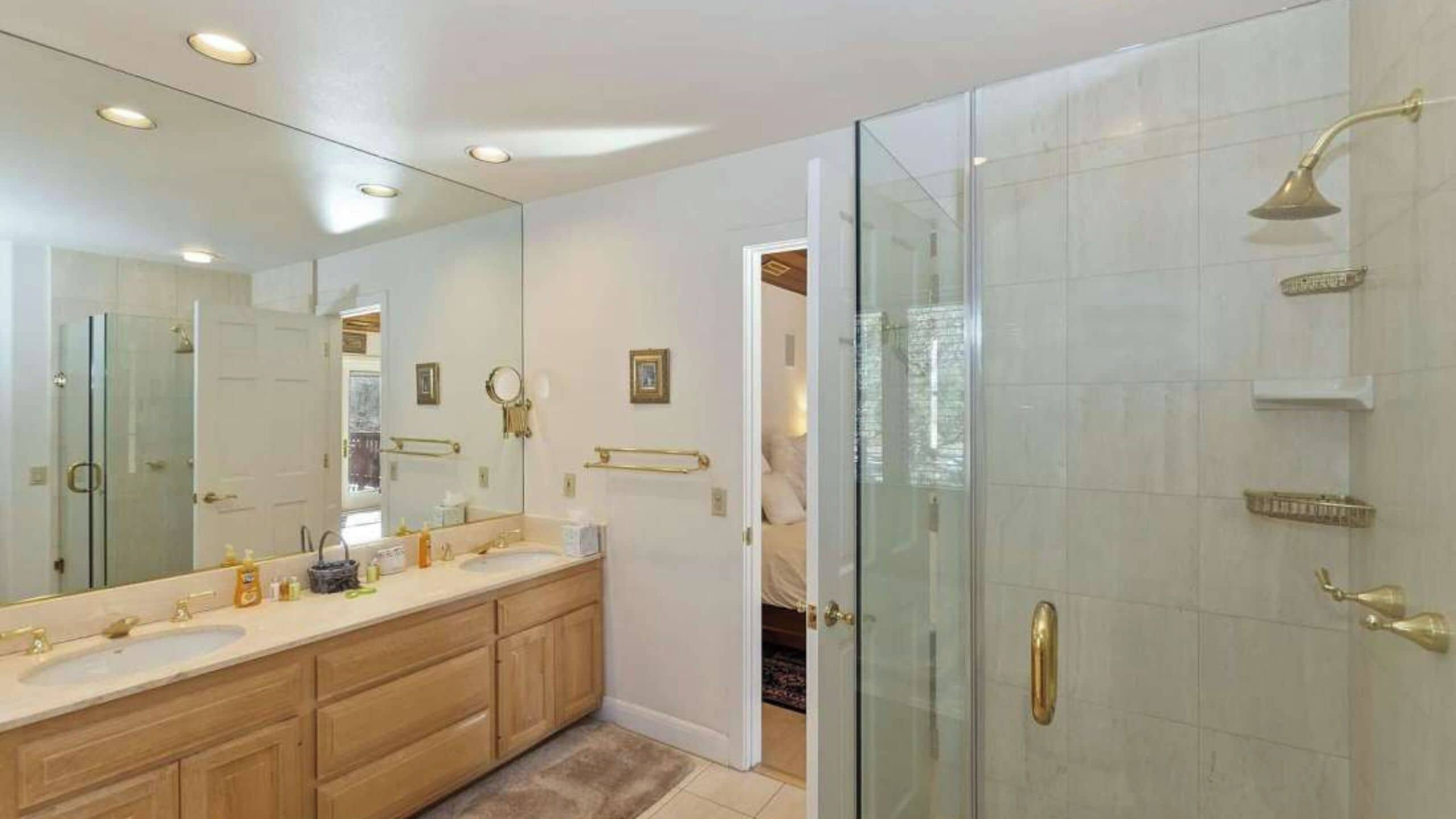 A modern bathroom with a glass shower enclosure, a large mirror, and a vanity with dual sinks.