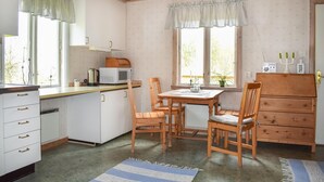 A compact kitchen with white cabinets, a microwave, and a coffee maker. There is a dining table with chairs, a wooden cabinet, and a window with curtains. - Awesome home in ånimskog with WiFi (Ånimskog)