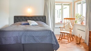 A bedroom with a large bed, a rocking chair, and a window with curtains. - Awesome home in ånimskog with WiFi (Ånimskog)