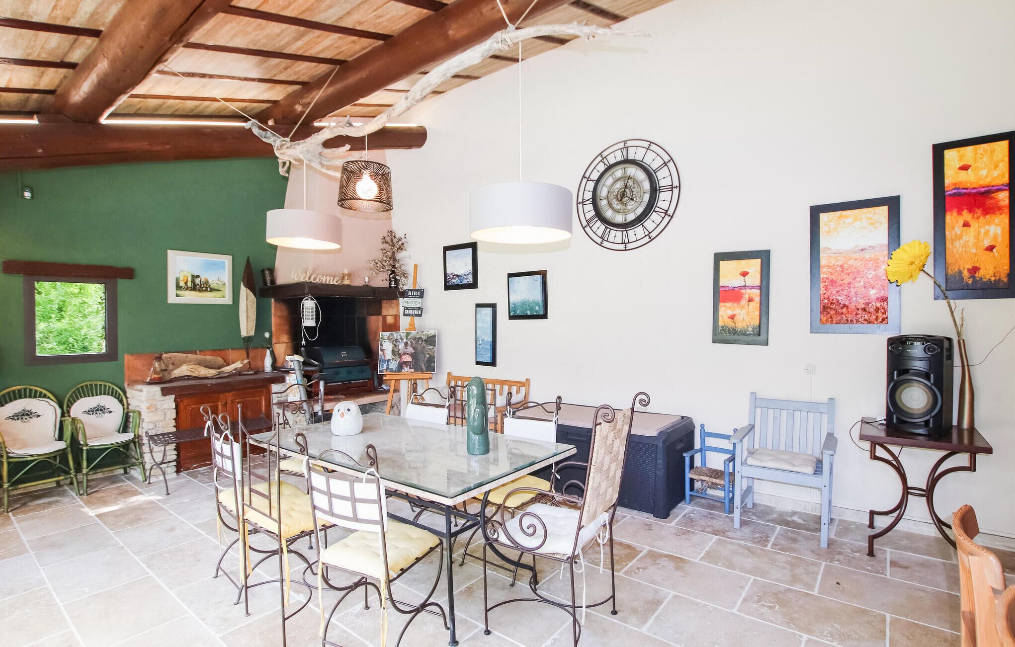 Un comedor con mesa de vidrio y sillas metálicas, chimenea y varias obras de arte enmarcadas en las paredes.
