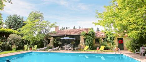 A swimming pool with lounge chairs and a covered patio area.