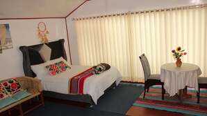 Une chambre à coucher comprenant un lit, une chaise, une petite table avec un vase et une décoration murale.