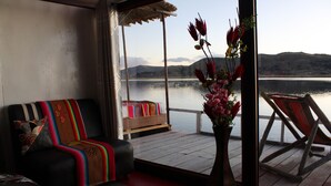 Une pièce avec un canapé, une terrasse en bois, une chaise et une vue sur un lac.