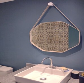 A bathroom with a white sink, a mirror with a patterned frame, and a blue wall.