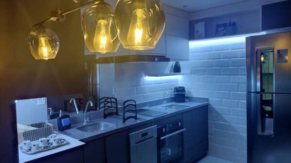 A modern kitchen with a stainless steel refrigerator, a double sink, and a dishwasher.
