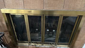 A sliding glass door with a brass frame, a small planter with plants, and a textured wall.