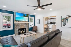 Ein modernes Wohnzimmer mit Kamin, Fernseher und Essbereich.