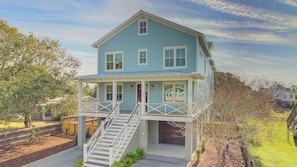A two-story house with a covered porch and a staircase leading to the main entrance.